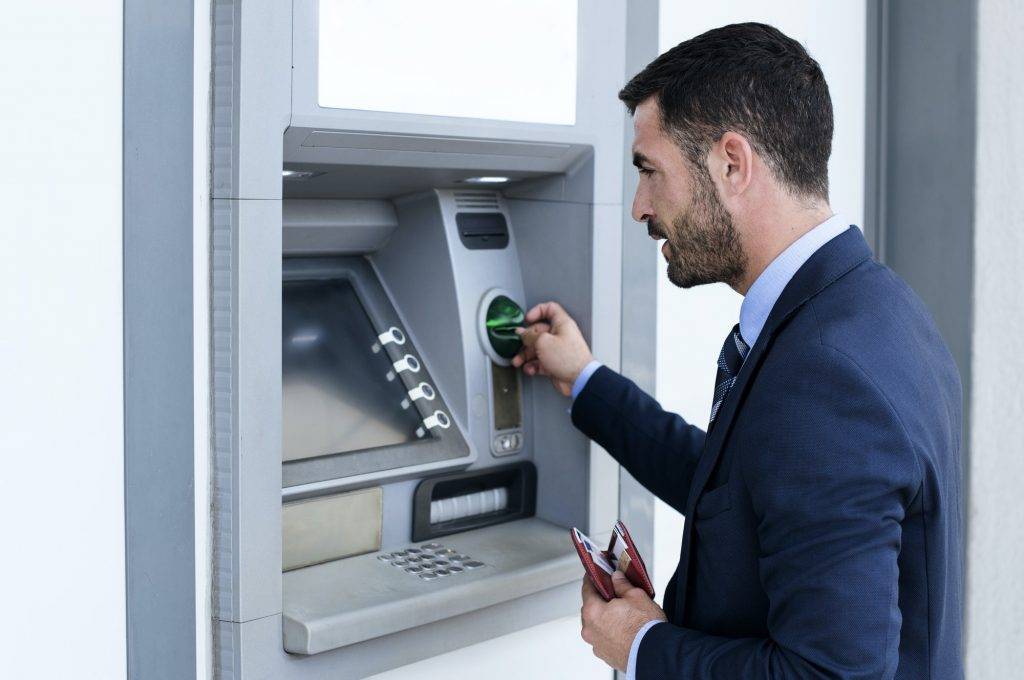 Side View Of Businessman Using Atm At Subway Station